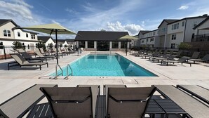 A swimming pool with lounge chairs and umbrellas, surrounded by buildings. - 3-bedroom Luxury townhome in brilliant Edmond 5 min to UCO (Edmond)