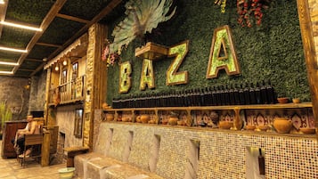 Un interior acogedor con una pared verde, vigas de madera y una zona de estar con cojines.