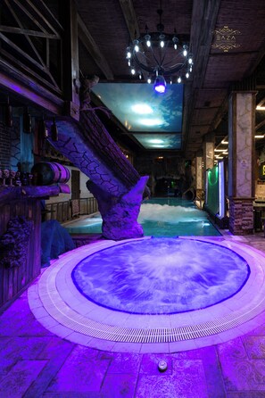 A hot tub area with a stone structure, a ceiling with a light fixture, and a pool. - BazaHotel&Spa (Mil)