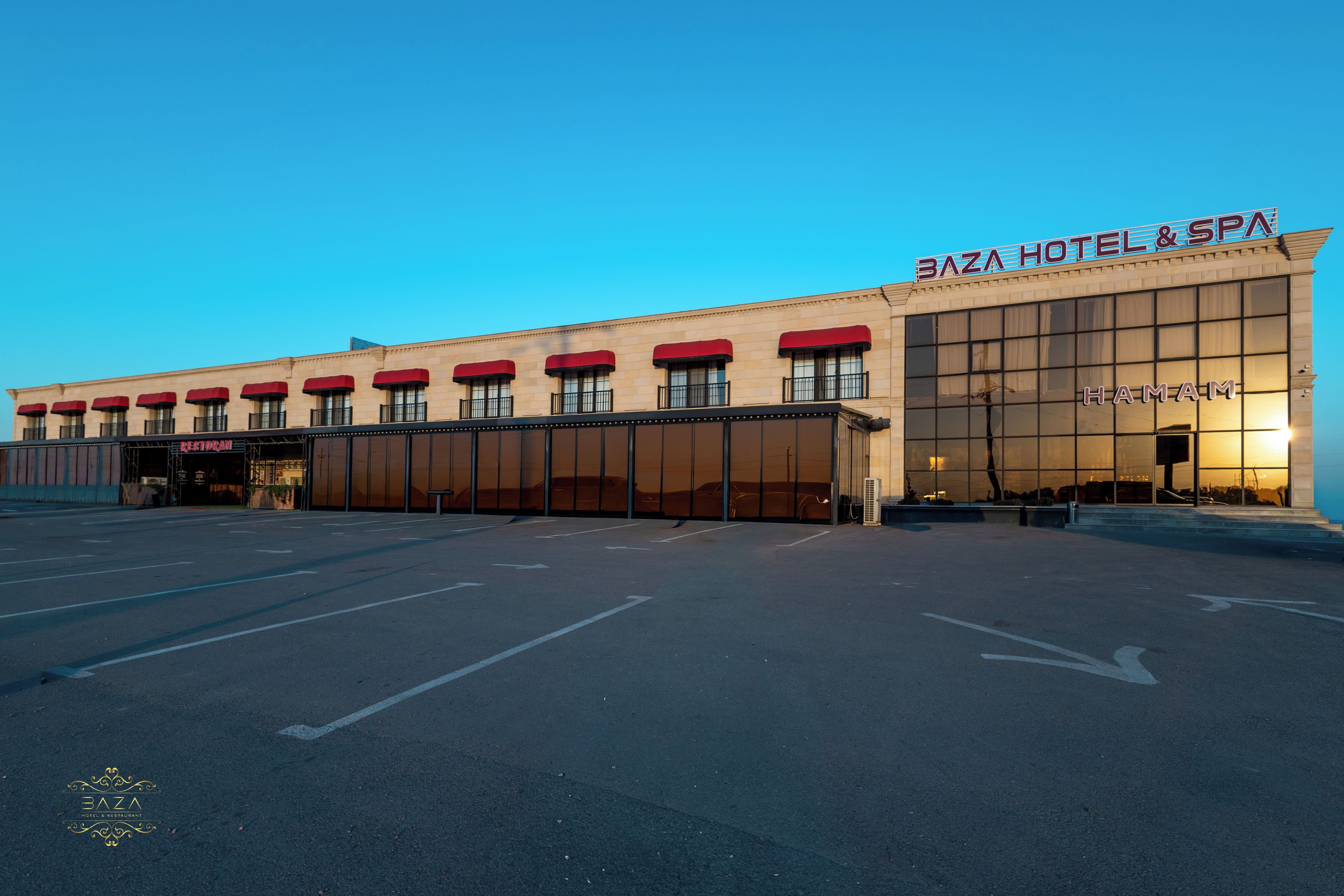 A hotel with a large parking lot and a prominent sign reading 'Baza Hotel & Spa'.