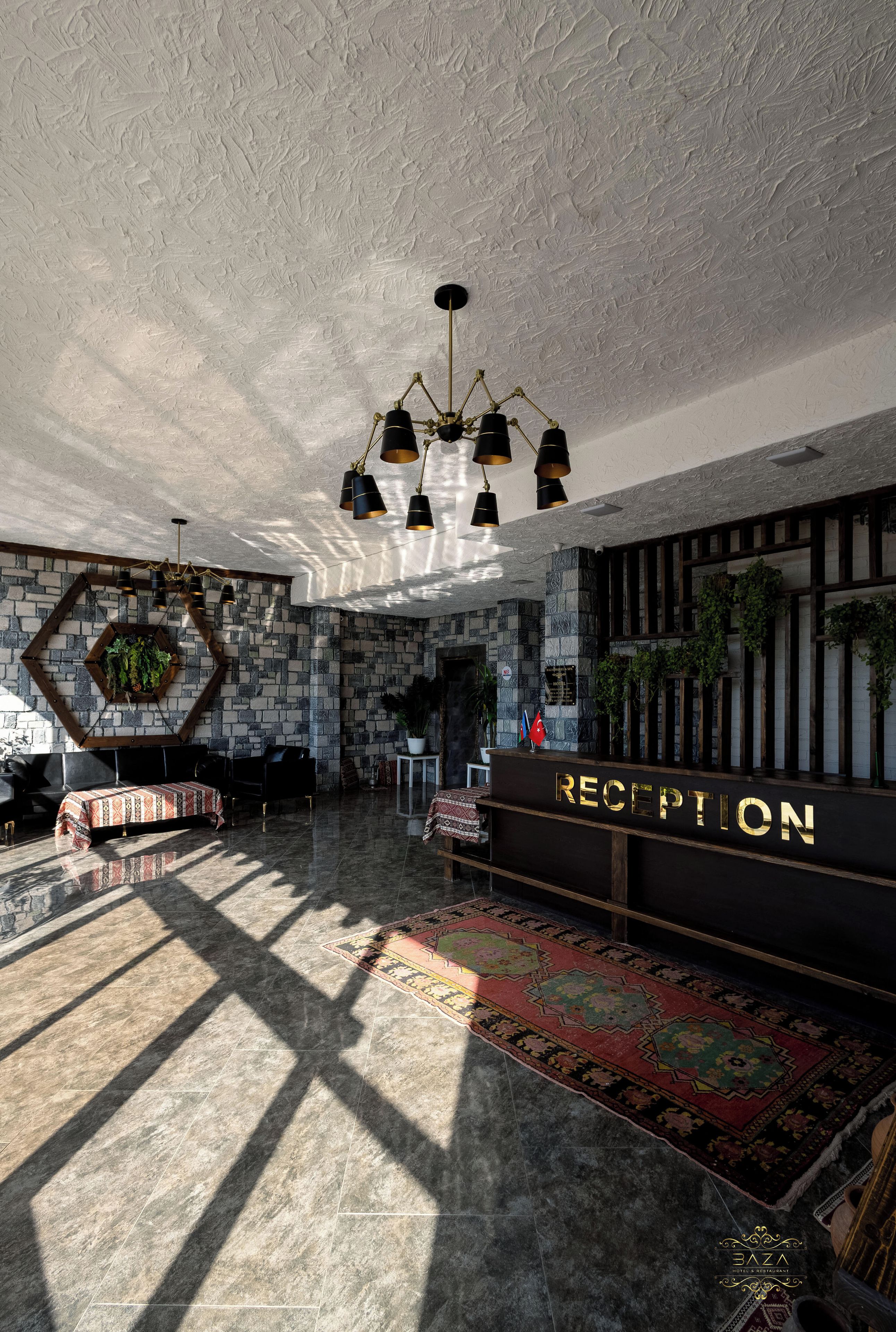 Een receptiezone met een stenen muur, een receptiebalie en een kroonluchter.