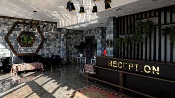 Een receptiezone met een stenen muur, een receptiebalie en een kroonluchter.