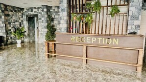 A reception desk with a 'RECEPTION' sign, surrounded by stone walls and potted plants. - BazaHotel&Spa (Mil)