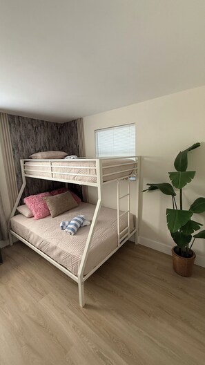 Ein Stockbett mit Fenster, einem Blumentopf und einem Holzboden.