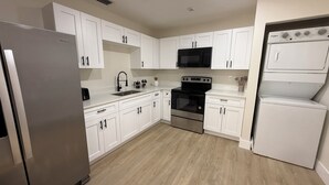 Uma cozinha moderna com armários brancos, eletrodomésticos de aço inoxidável, micro-ondas, forno e geladeira.