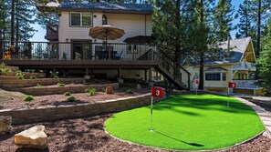 A residential property with a two-story house, a deck with outdoor furniture, and a mini-golf course. - Balboa Big Bear by Avantstay Hot Tub + Game Room + Firepit + Putting Green Near Bear Mountain (Big Bear Lake)