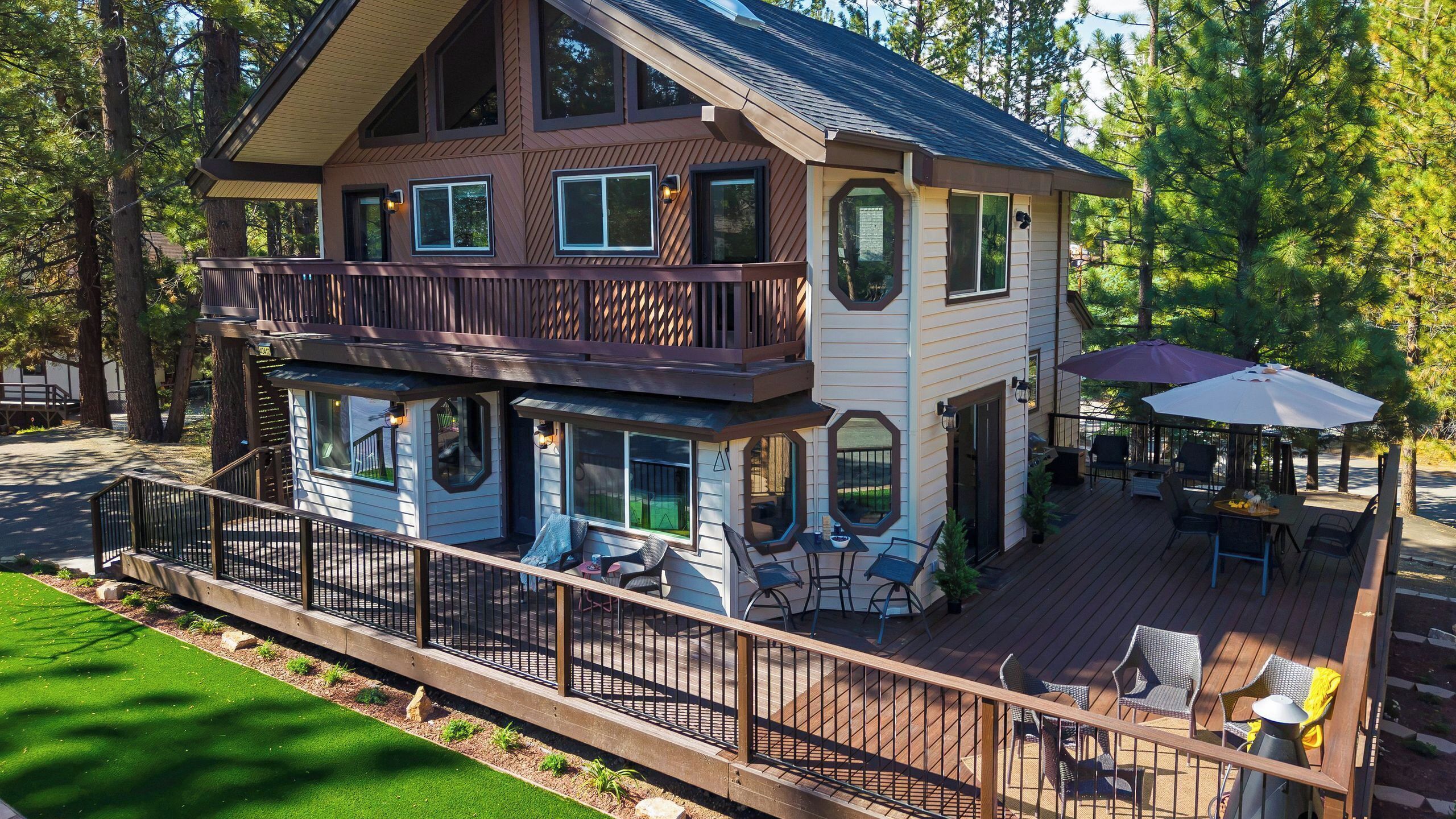 A two-story house with a balcony, outdoor seating, and a deck.