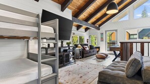 A spacious room with a bunk bed, a sofa, a coffee table, and a fireplace. - Balboa Big Bear by Avantstay Hot Tub + Game Room + Firepit + Putting Green Near Bear Mountain (Big Bear Lake)