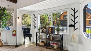 Una habitación con una estantería, una silla, una planta y una ventana con vistas al exterior.