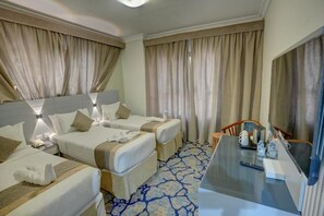 Ein Hotelzimmer mit zwei Betten, einem Schreibtisch, einem Stuhl und einem großen Spiegel.