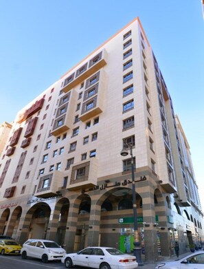 Ein mehrgeschossiges Hotel mit moderner Architektur, das eine markante Eingangshalle mit Bögen und einem gut sichtbaren Schild aufweist.