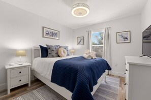 Ein Schlafzimmer mit einem Bett, Nachttischen, einem Schreibtisch und Kunstwerken an den Wänden.