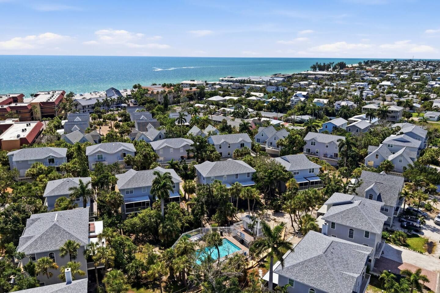 A coastal residential area with houses, a swimming pool, and a view of the ocean.