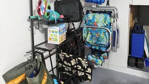 Ein Abstellraum mit mehreren Taschen und Koffern, einem Ventilator und einer blauen Wand.