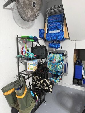 Ein Abstellraum mit mehreren Taschen und Koffern, einem Ventilator und einer blauen Wand.