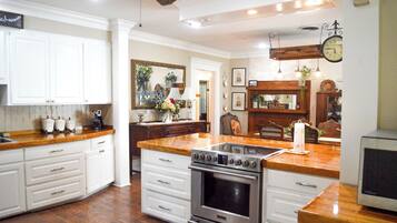 A kitchen with white cabinetry, a stainless steel stove, and a wooden countertop.