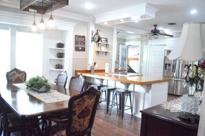 A dining area with a wooden table, chairs, and a kitchen in the background.
