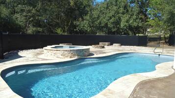 A swimming pool with a stone border and a stone fire pit.