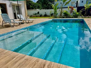 A rectangular swimming pool with clear blue water, surrounded by a wooden deck and a few lounge chairs. - Villa Pura Vida 4BR private Villa with large Pool & Bungalow (Las Terrenas)