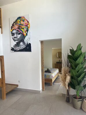 A room with a bed, a large painting on the wall, and a potted plant. - Villa Pura Vida 4BR private Villa with large Pool & Bungalow (Las Terrenas)