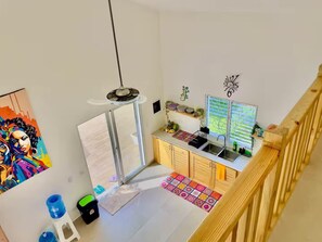 A modern kitchen with a central island, a dining area with a view, and a staircase leading to an upper level. - Villa Pura Vida 4BR private Villa with large Pool & Bungalow (Las Terrenas)