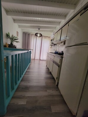A kitchen with a refrigerator, cabinets, and a wooden floor. - JV BEACHFRONT APARTMENT: YOUR DREAM OCEANVIEW SPOT (Añasco)
