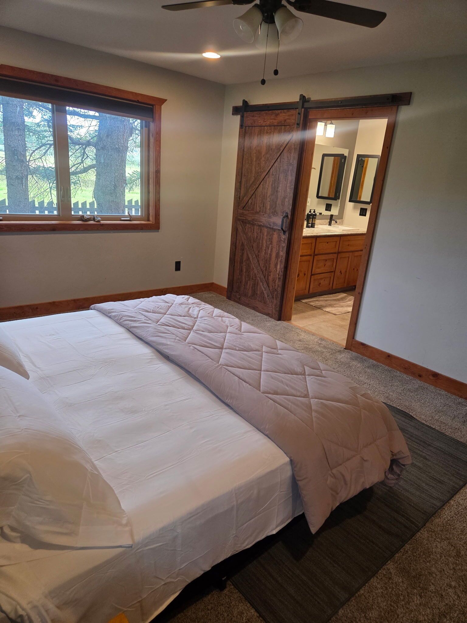 Ein Schlafzimmer mit einem großen Bett, einer Schiebetür zu einem Badezimmer und Blick ins Freie.