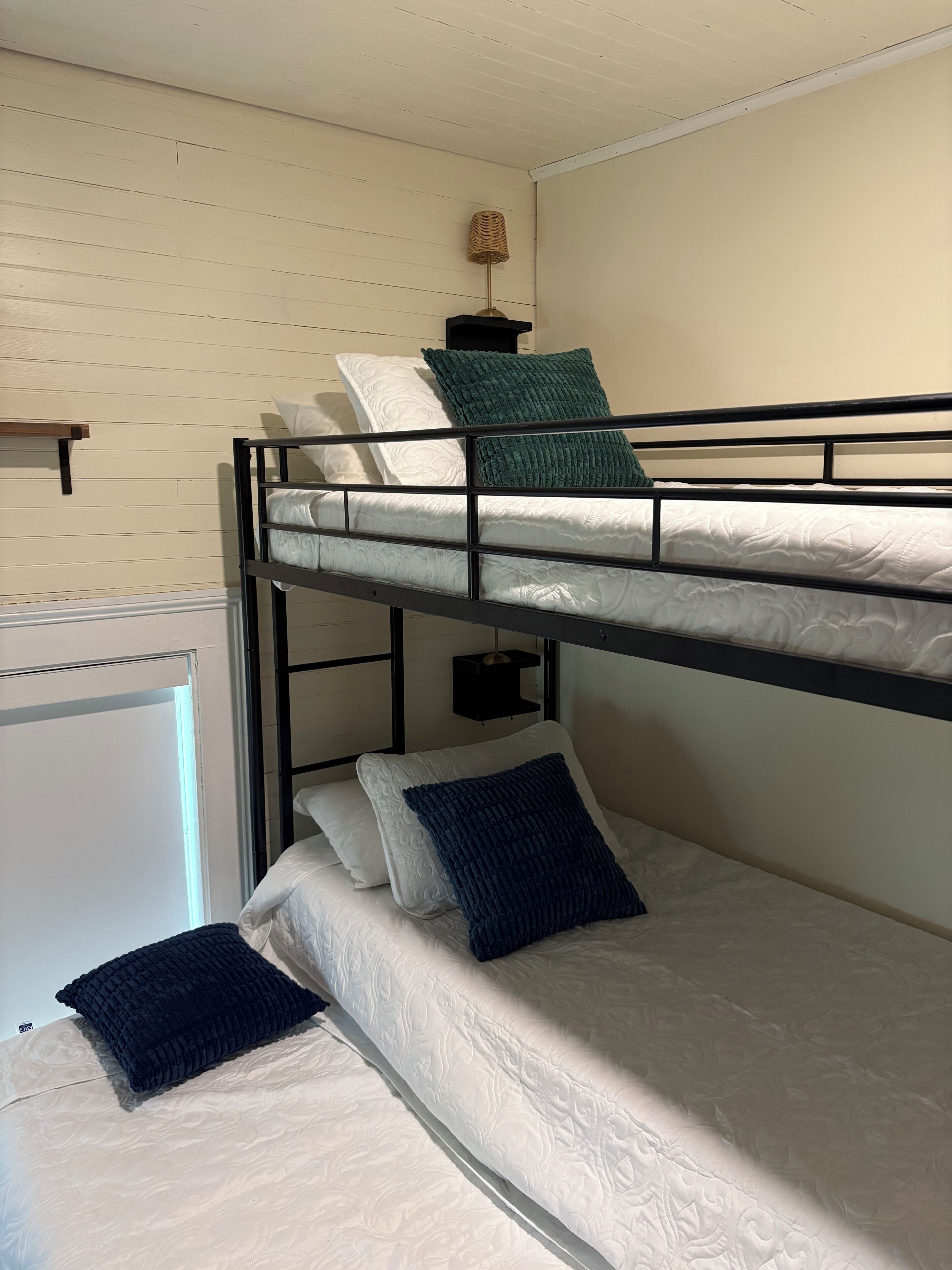 Un lit superposé à deux niveaux, une petite étagère et une lampe.