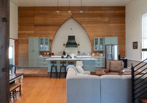 A modern kitchen with a central island, wooden cabinetry, and a vaulted ceiling.