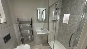 A modern bathroom with a glass-enclosed shower, a white sink, and a toilet. - High Wycombe Apartments (High Wycombe)