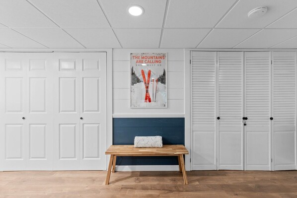 A room with a bench, a wall-mounted poster, and white doors.