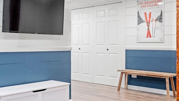 Una habitación con paneles de pared blancos y azules, un televisor montado, una puerta blanca y un cartel en la pared.