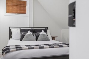 A bed with a black frame, white bedding, and gray pillows with mountain designs.