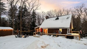 Una cabaña con terraza, rodeada de nieve y luces cálidas.