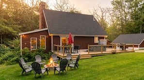 A cabin with a deck, outdoor seating, and a fire pit.