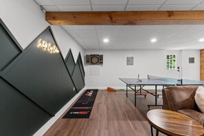 A room with a ping pong table, dartboard, and a wall-mounted dartboard.