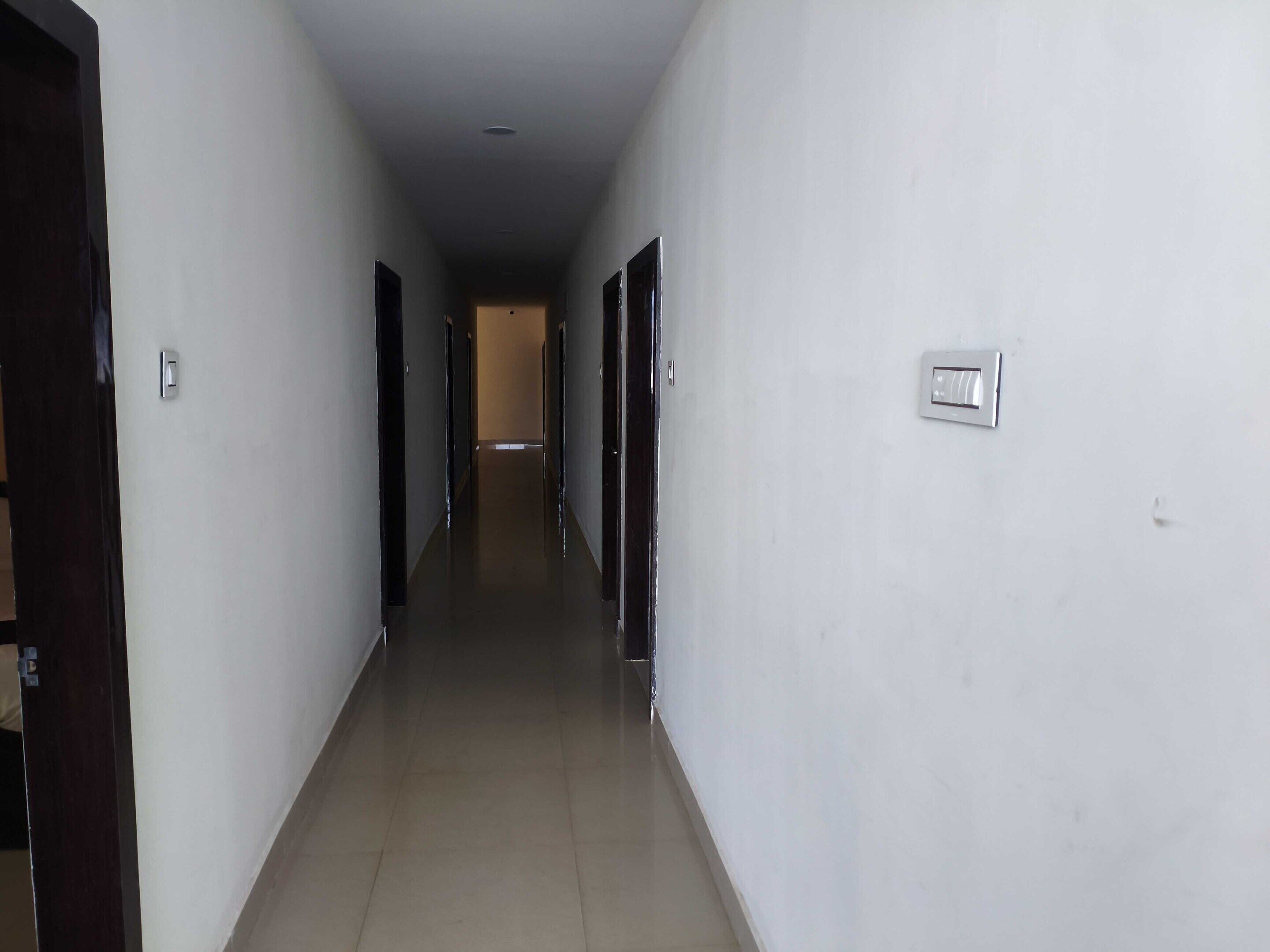 A long, narrow hallway with doors on both sides, leading to a room at the end.