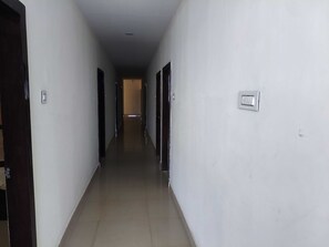 A long, narrow hallway with doors on both sides, leading to a room at the end. - Deluxe SLN Terminus Gachibowli (Hyderabad)