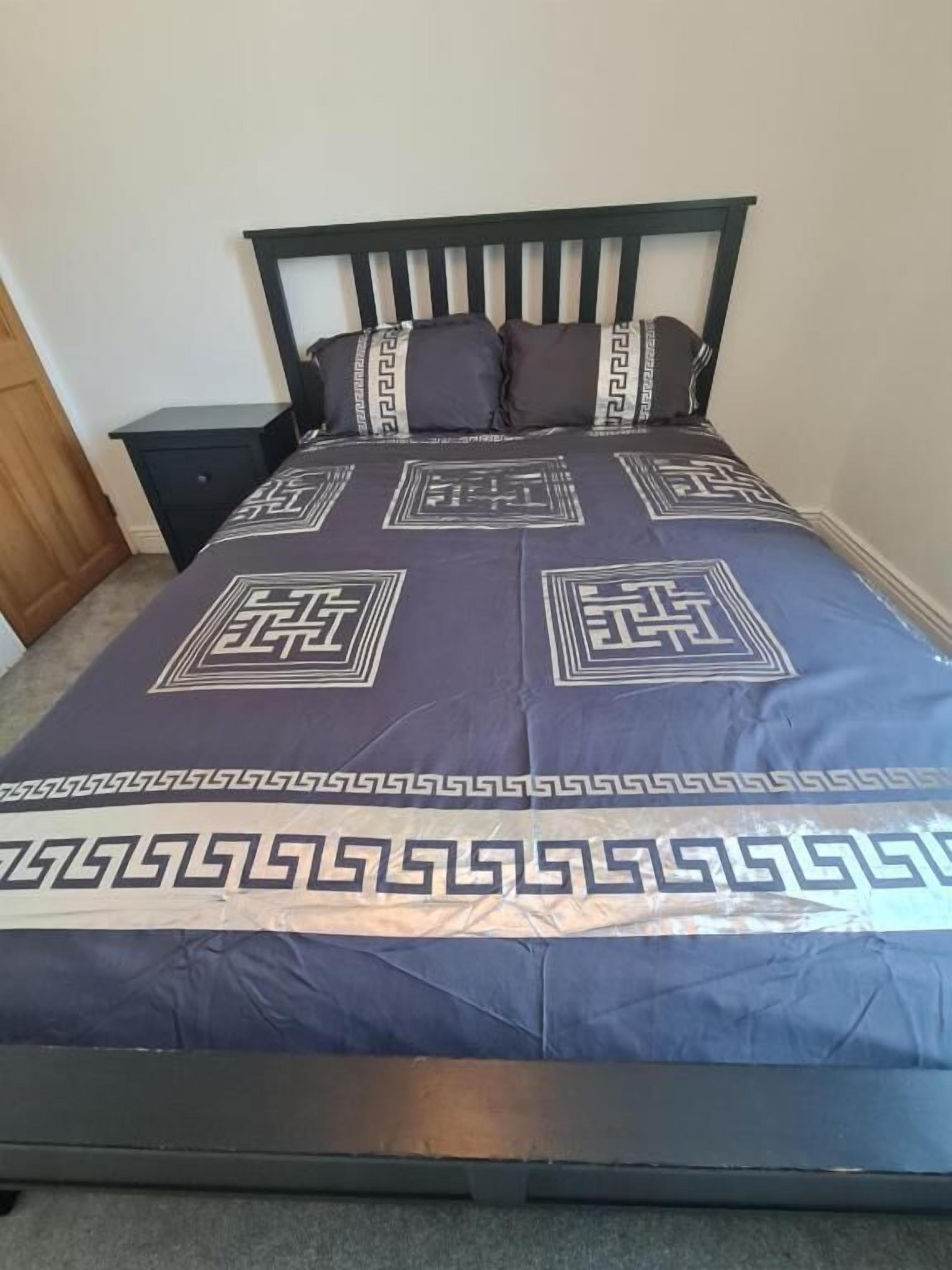 A bed with a dark headboard and a patterned bedspread.