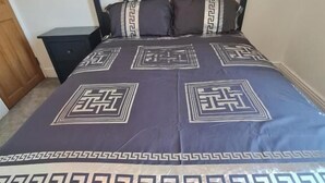 Uma cama com cabeceira escura e colcha estampada.