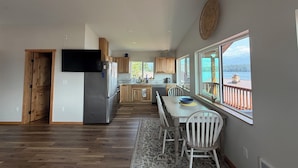 Een ruime keuken met een groot eiland, houten kasten en uitzicht op een meer door de ramen.