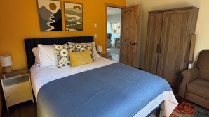 Een slaapkamer met een bed, nachtkastje, kledingkast en plafondventilator.