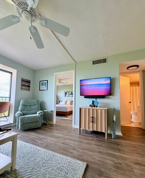 Ein Wohnzimmer mit Deckenventilator, Fernseher, Sofa und Holzschrank.
