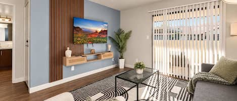 Una sala de estar moderna con un televisor de pantalla plana, un sofá, una mesita de centro y una alfombra estampada.