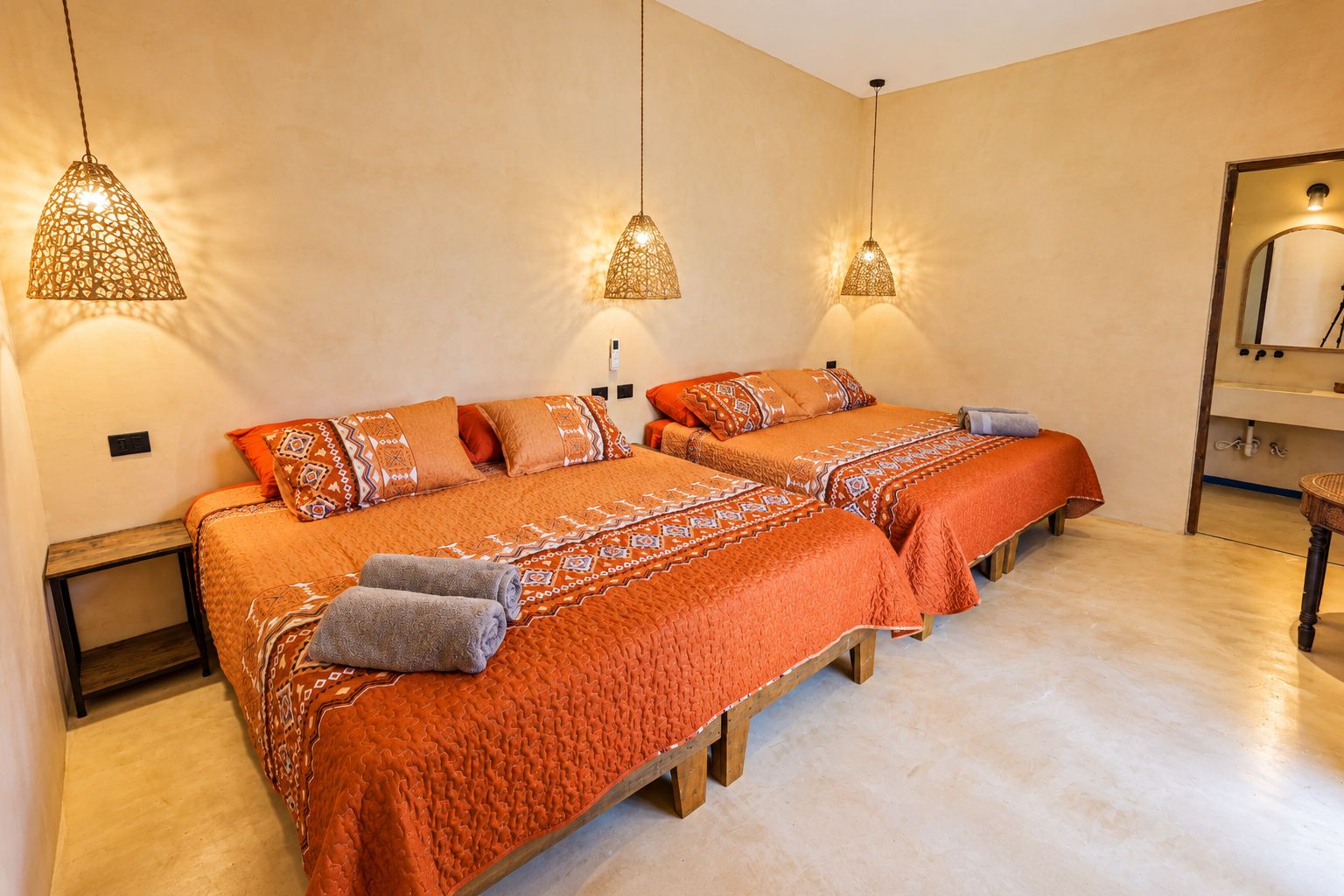 Une chambre d’hôtel avec un grand lit, deux tables de chevet et trois lampes suspendues.