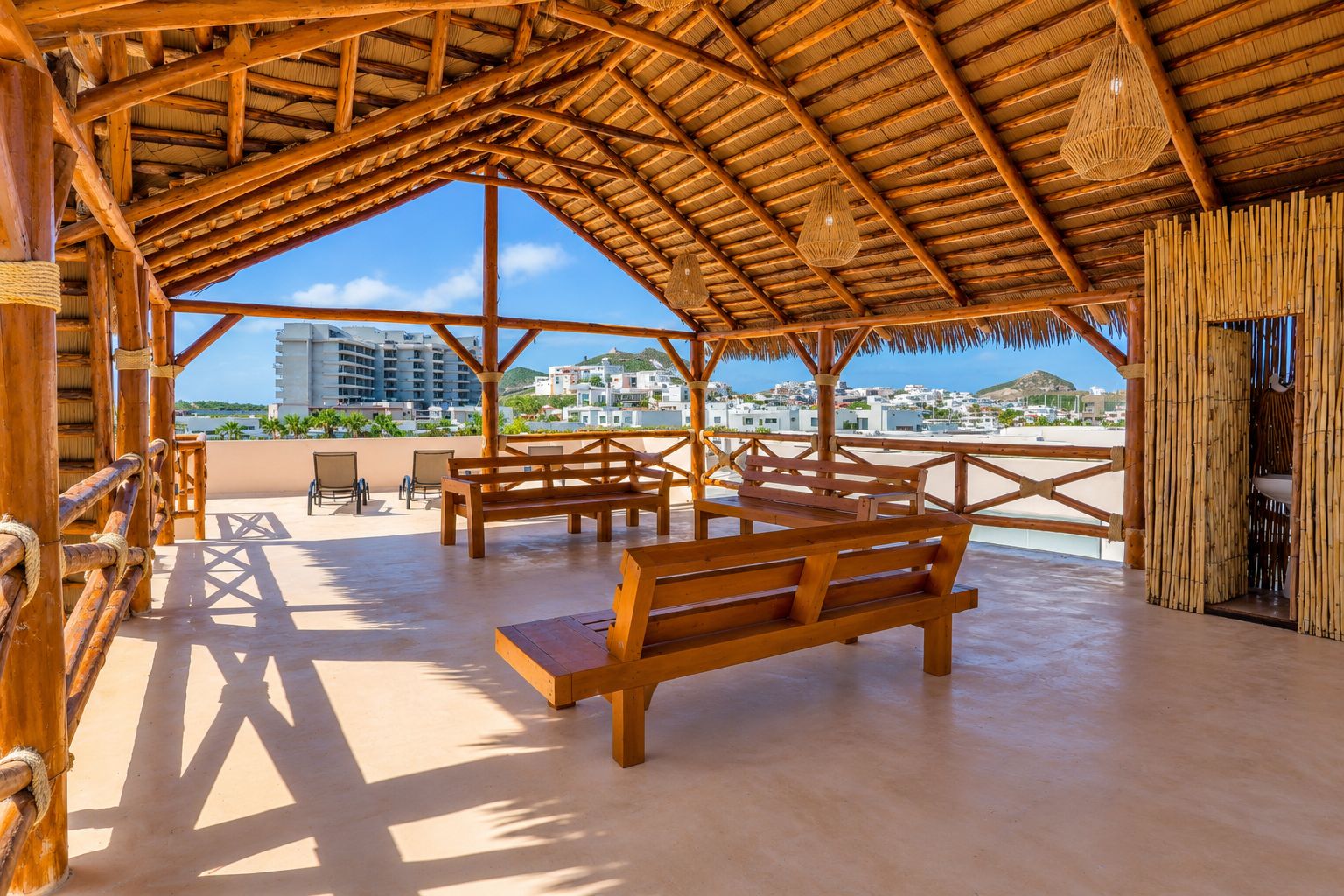 Un espace extérieur aménagé en bois, avec des bancs et des tables, offrant une vue sur une ville côtière.