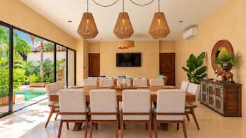 Une salle à manger avec une grande table, des chaises et des luminaires suspendus.