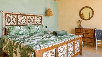 A room with a bed, a hanging light fixture, a mirror, and a wooden dresser.