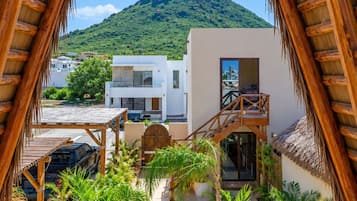 Une vue depuis un balcon en bois donnant sur une piscine, avec une montagne et des bâtiments modernes en arrière-plan.