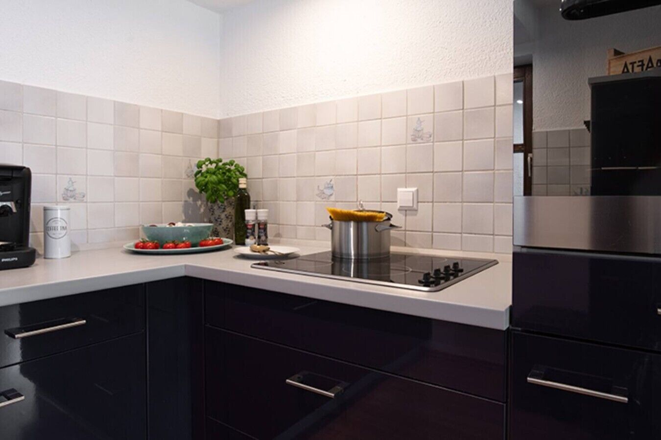 A modern kitchen with a built-in stove, dark cabinets, and white tiled backsplash.